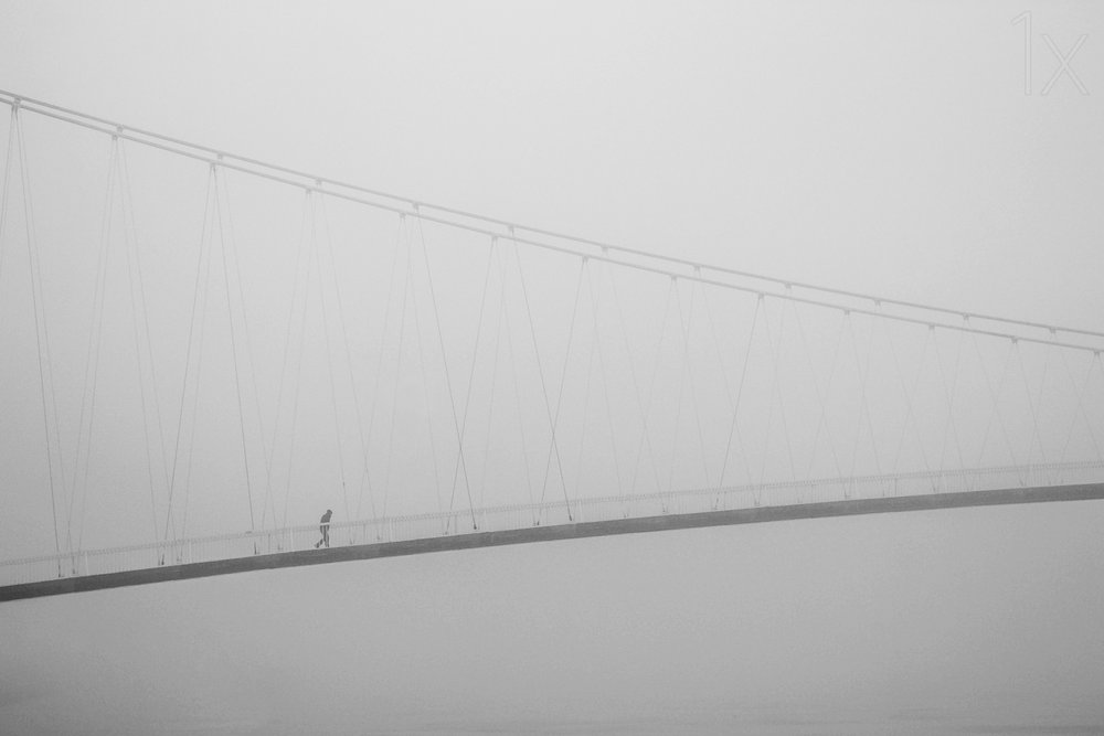Een eenzame wandeling over een mistige brug door Krunoslav Nevistic
