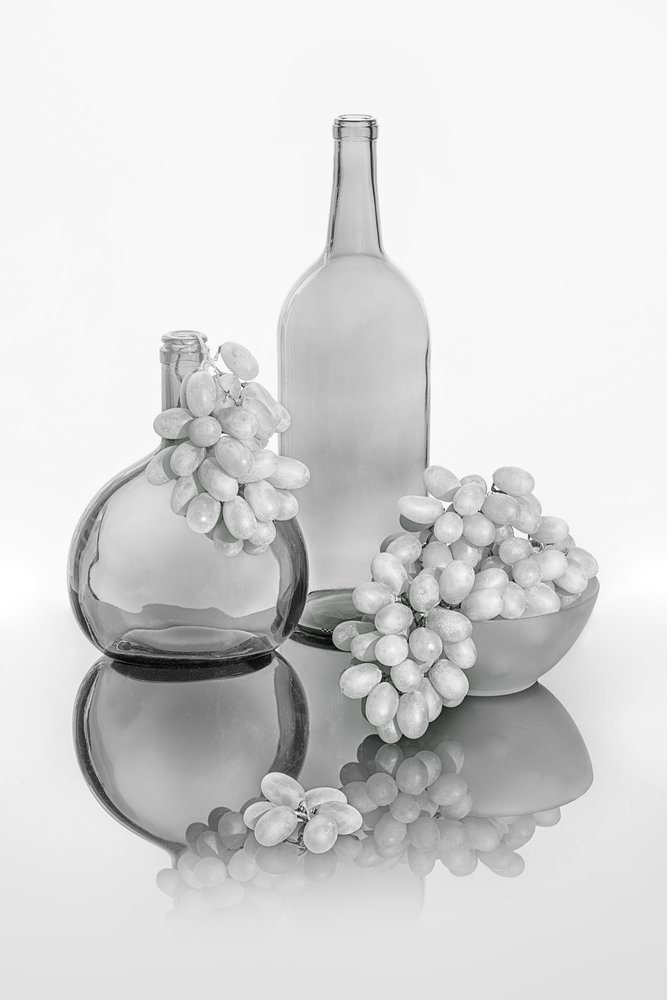 Monochrome glazen flessen met druivenmotief door Lydia Jacobs