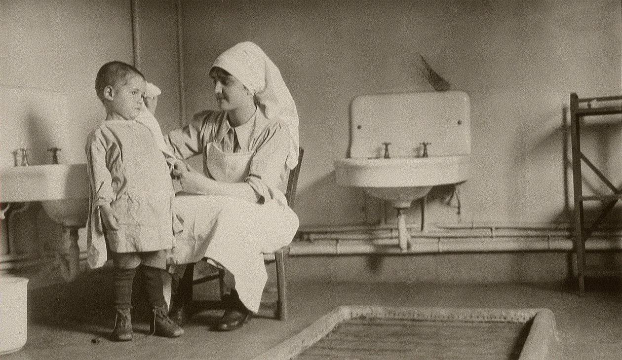Verpleegster verzorgt een ziek kind in de kolonies van Passay en Saint-Quentin voor vluchtelingen en wezen, 1919 door American Photographer