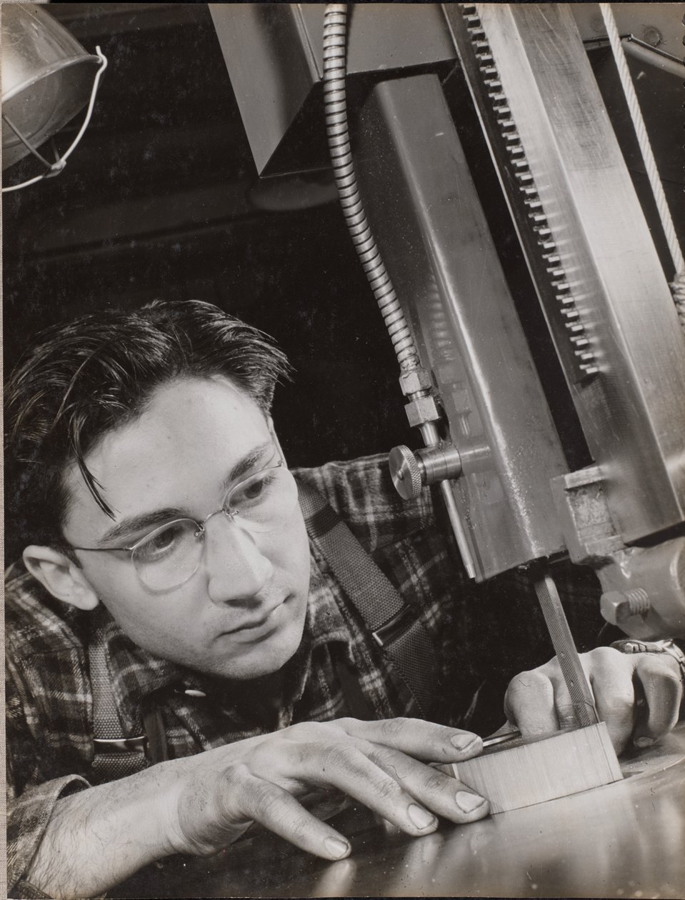 [Man met bril werkt geconcentreerd met een industriële vijl]. door Arnold Eagle