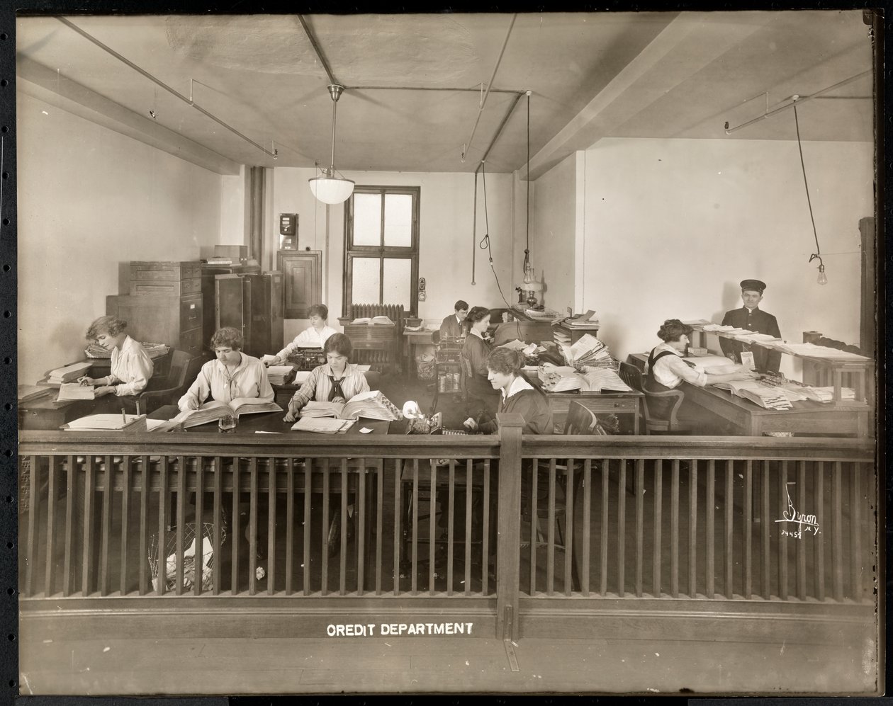 Een man en vrouw die werken in het kredietkantoor van de Mantle Lamp Co. of America, New York, 1915-16 door Byron Company