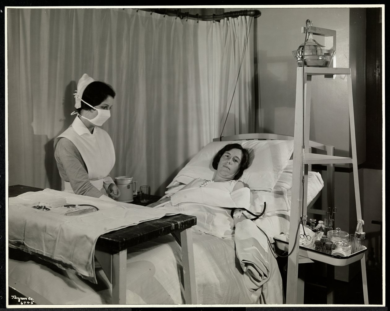 Een gemaskerde verpleegster met een patiënt in een kamer in het Sloane Medical Hospital, Broadway en 168th Street, New York, 1932 door Byron Company