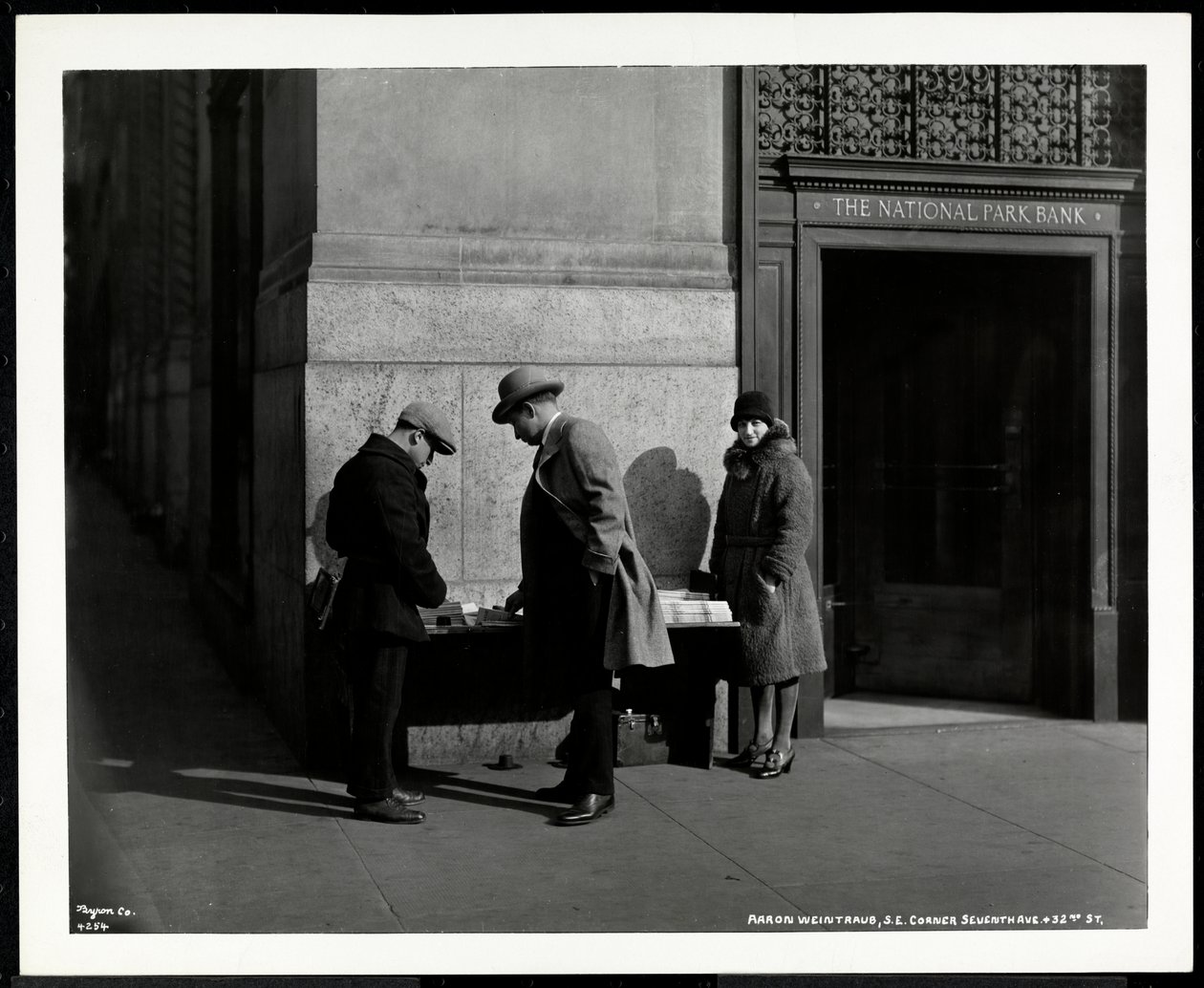 Blinde krantenverkoper, Aaron Weintraub, bij zijn stand op de zuidoostelijke hoek van 7th Avenue en 32nd Street, New York, 1930 door Byron Company