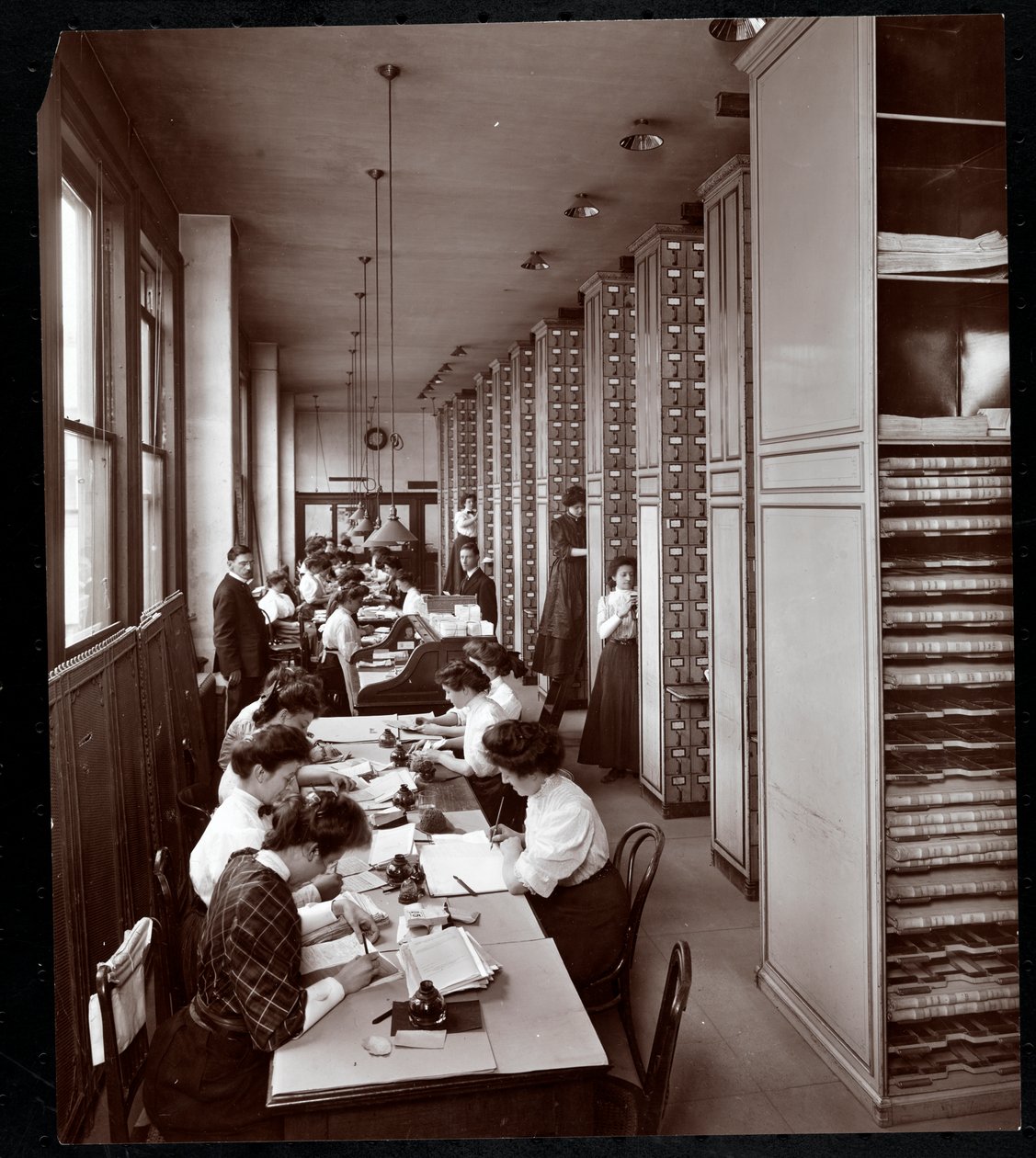 Vrouwen die werken in een archiefkamer, onder mannelijke supervisie, bij de Metropolitan Life Insurance Co. aan 23rd Street en Madison Avenue, New York, 1907 door Byron Company