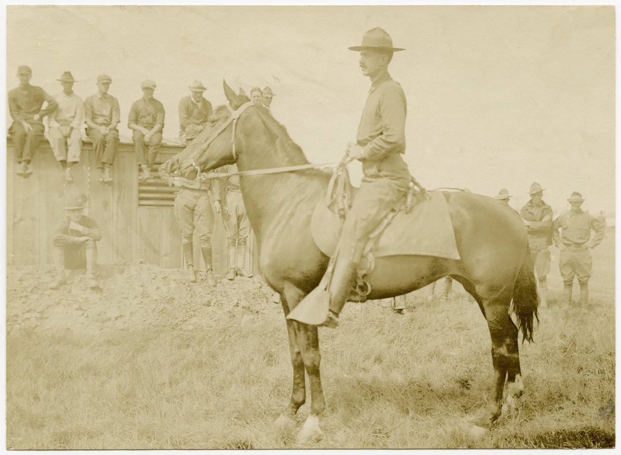 Soldaten verzameld rond en kijkend naar een soldaat in uniform te paard op een grasveld door Carl Michel