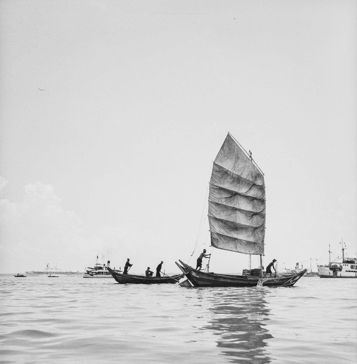 Een sampan onder zeil en een die wordt geroeid in de haven van Penang door David Watkin Waters