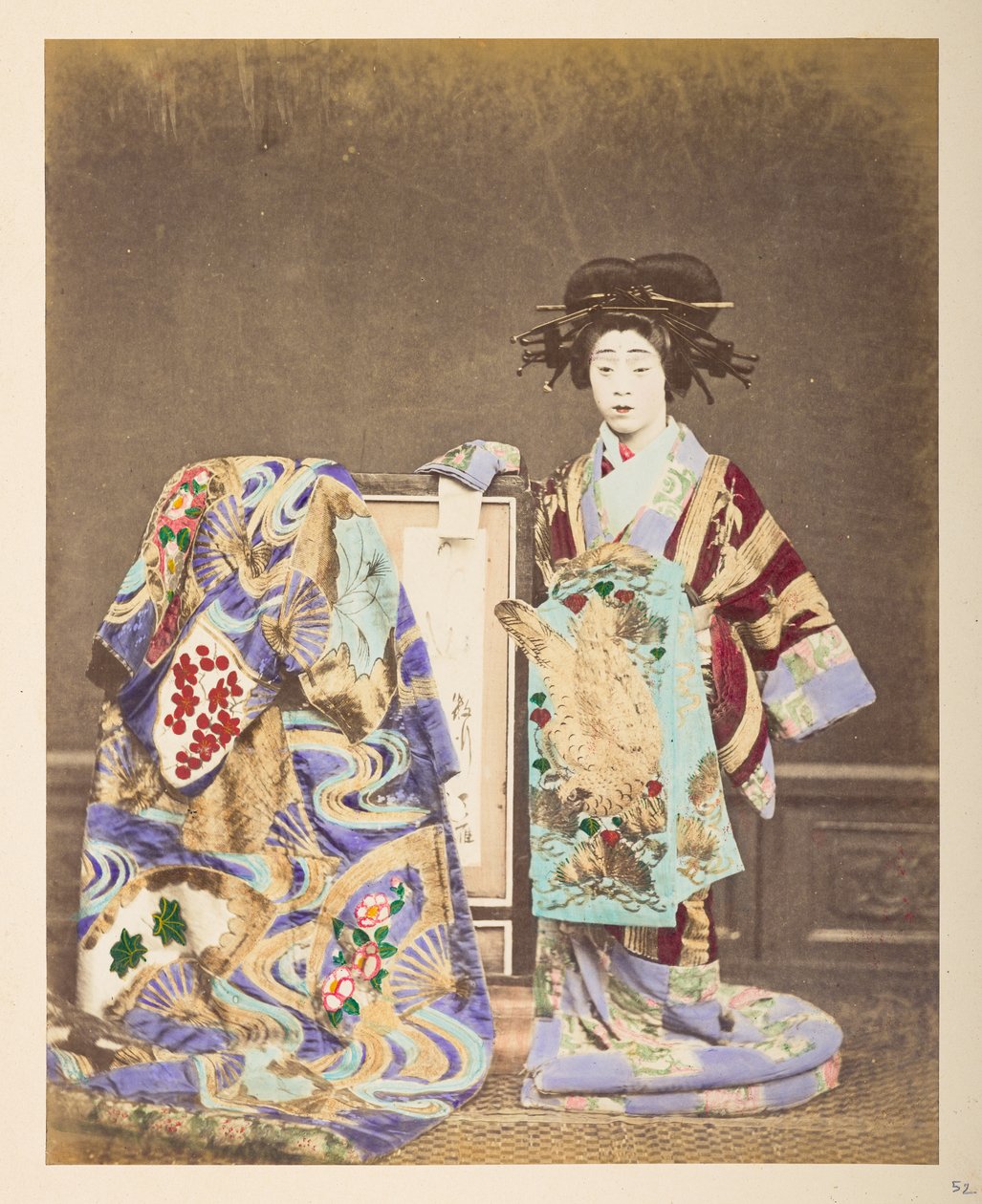 Japanse vrouw in traditionele kleding, Volledig staand studioportrait van een vrouw die een uitgebreide kostuum en kapsel draagt, met een andere mantel over het frame naast haar, Fotograaf: Onbekend Lucas Collectie: Fotografisch verslag van de wereldreis v door English Photographer