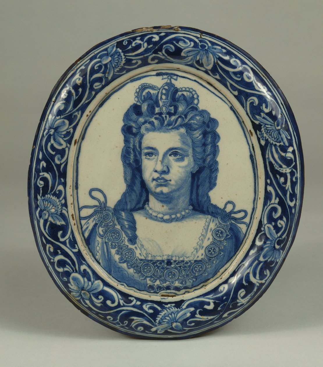 Een Delfts blauw en wit ovaal koninklijk portretplaquette van Koningin Anne, waarschijnlijk Londen, ca. 1705 door English School
