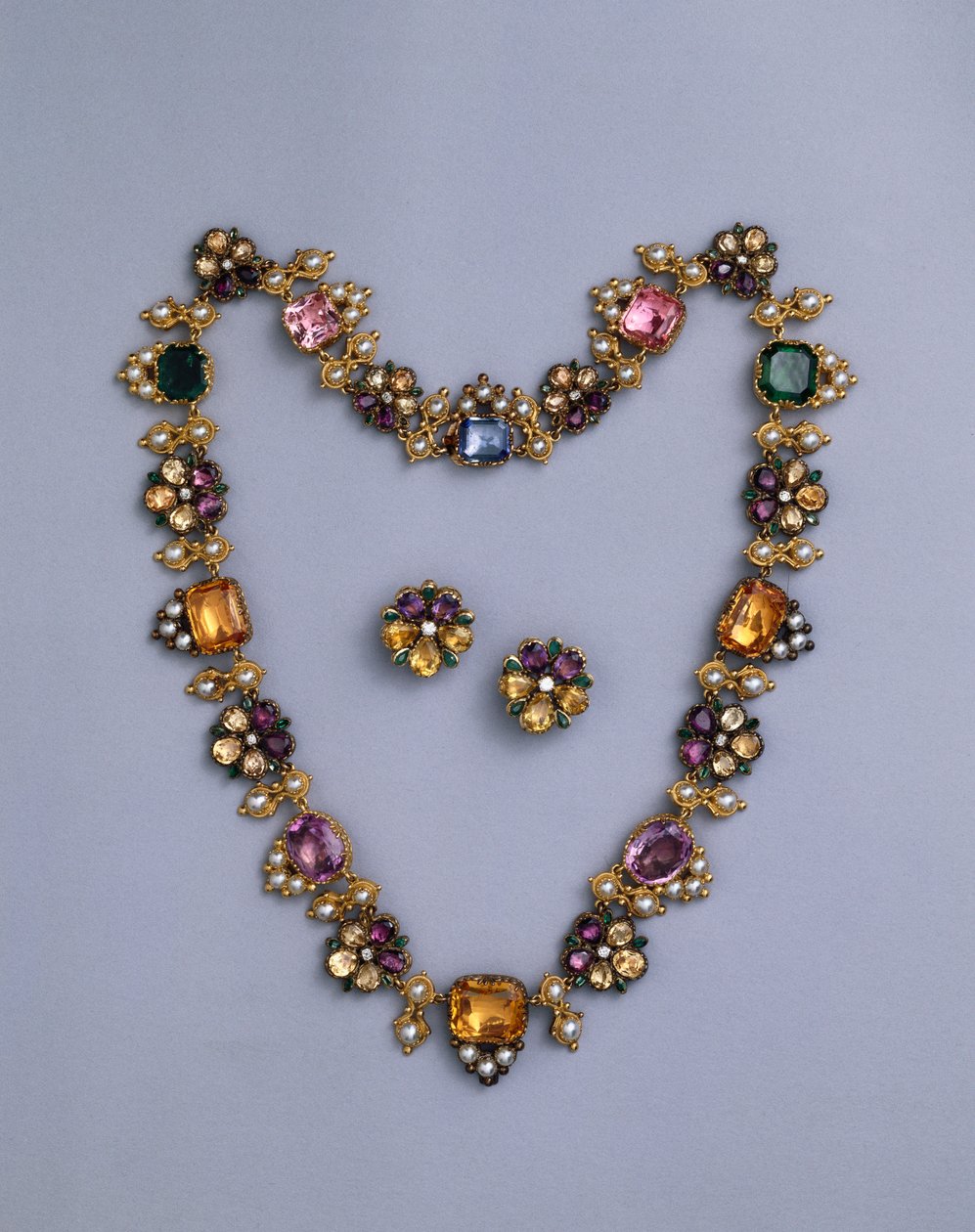 Een fijne Regency gouden en met juwelen versierde ketting met kussen geslepen topaas, amethisten, roze toermalijnen, smaragden, saffieren en peridots, met een paar bloemvormige oorbellen, c.1810 door English School