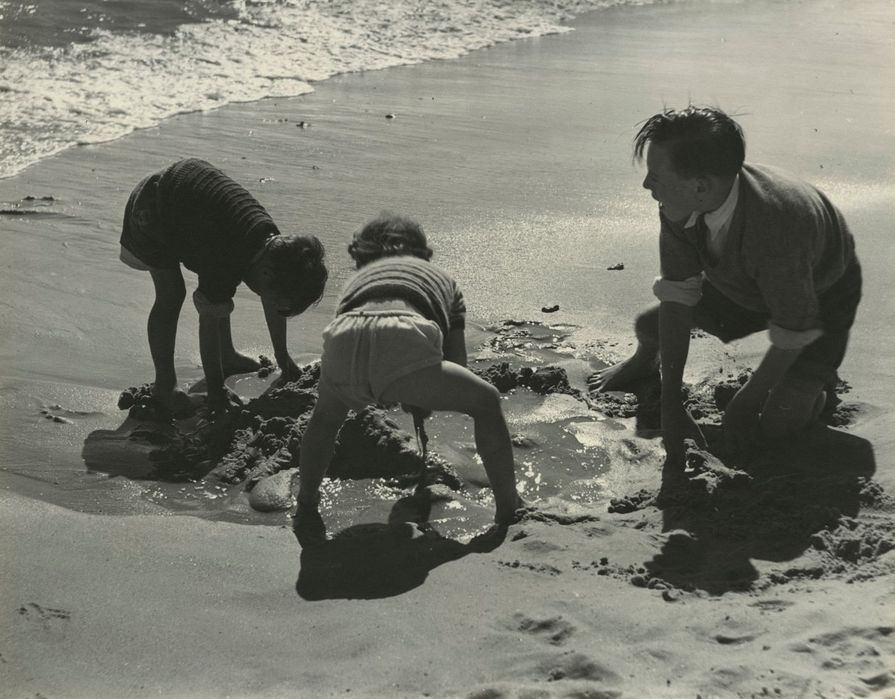 Drie kinderen spelen met zand op het strand door Godfrey Macdominic