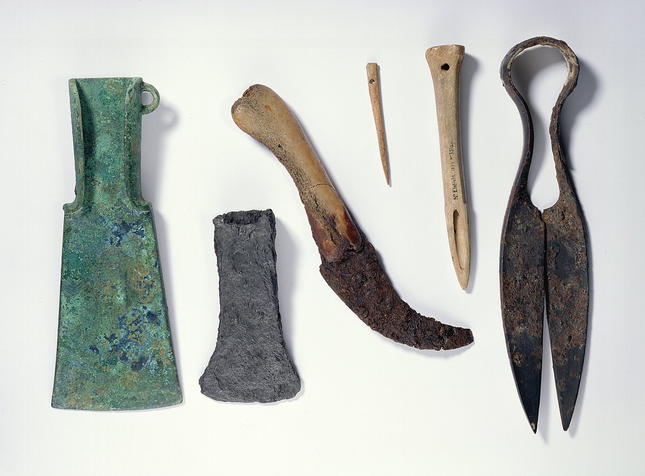 Selectie van gereedschappen: L-R: vroege ijzertijd bronzen bijl met omgebogen vleugels; latere ijzeren bijl; mes met een handvat van bot; botnaald; botpriem; ijzeren schaar door Iron Age
