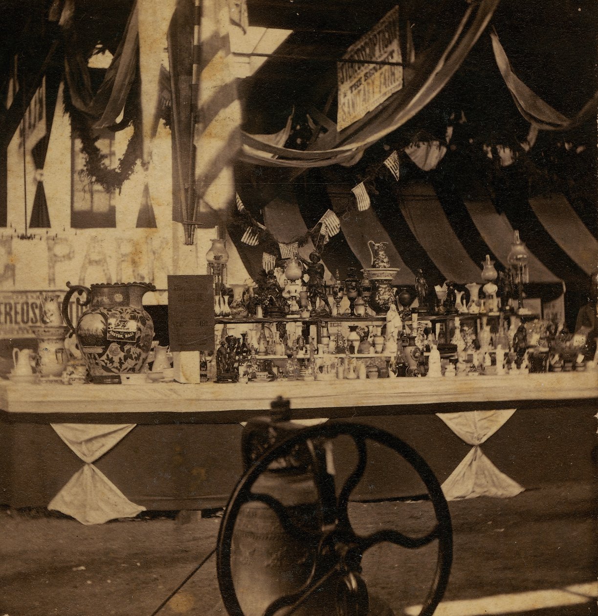 Half-view stereograaf van tafel met verschillende stukken koopwaar door J.A. Scholten