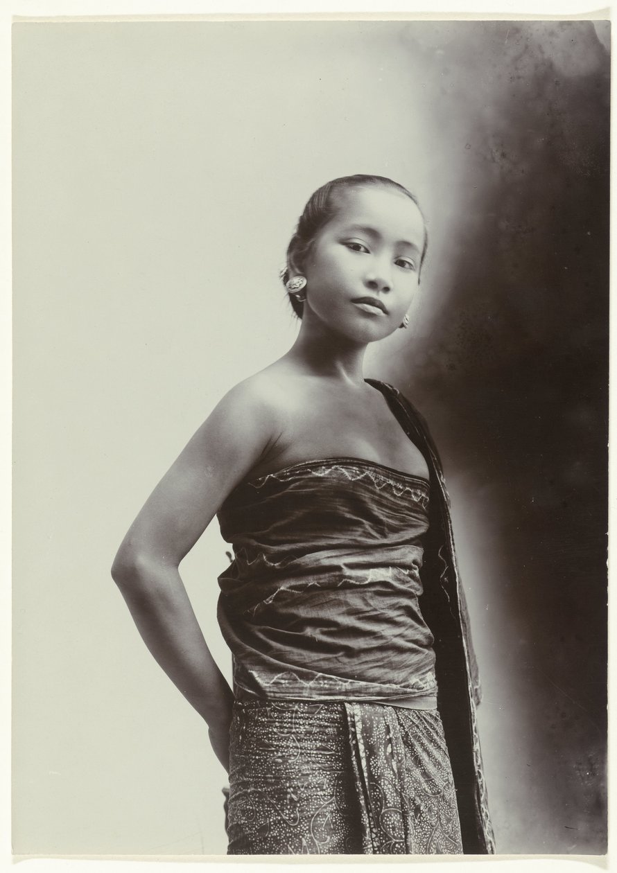 Studioportret van een jonge Javaanse vrouw in een sarong met batik motief door Kassian Cephas
