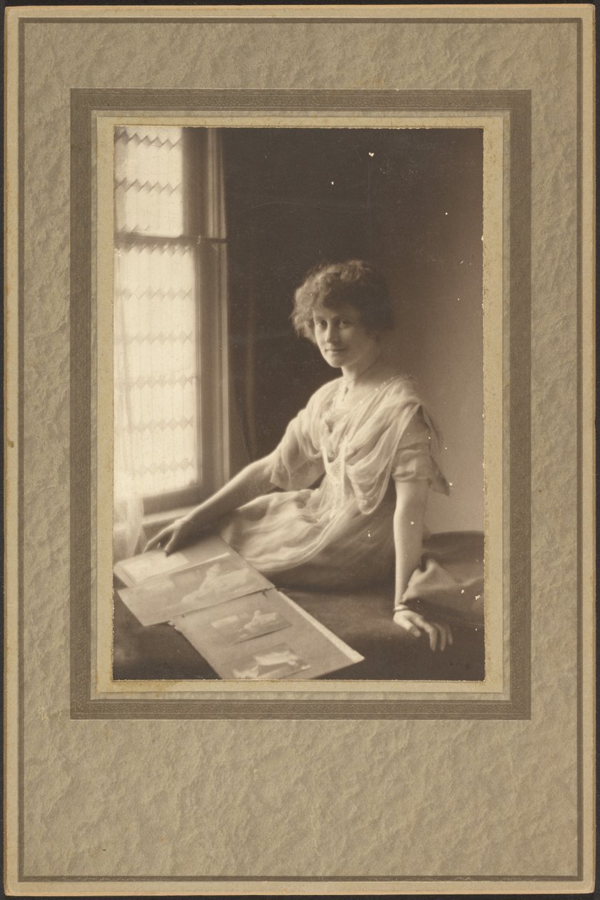[Portret van een vrouw die naar een album kijkt]. door Louis Fleckenstein