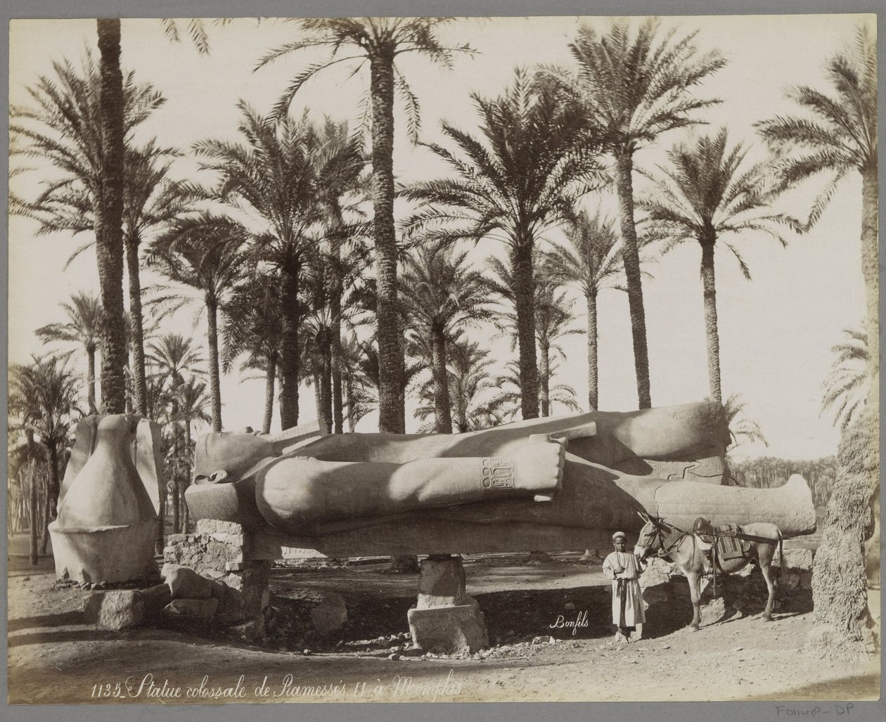 Liggend beeld van Ramses II in Memphis, op de voorgrond een jongen met een ezel door Maison Bonfils
