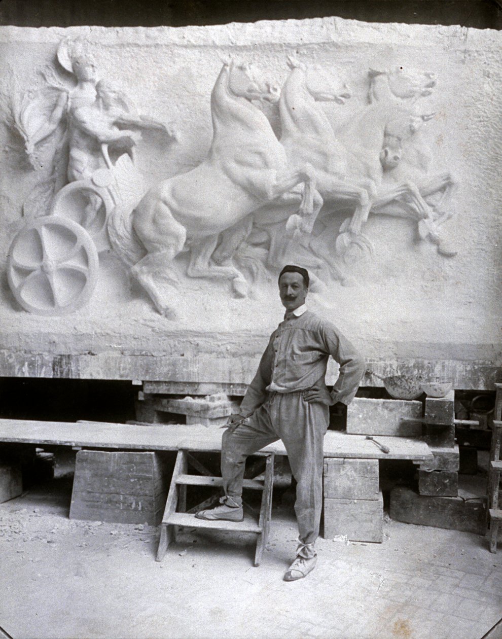 Volledig portret van de beroemde beeldhouwer Pietro Canonica. Hij poseert in zijn studio voor een marmeren hoogreliëf waar hij aan werkt door Mario Nunes Vais