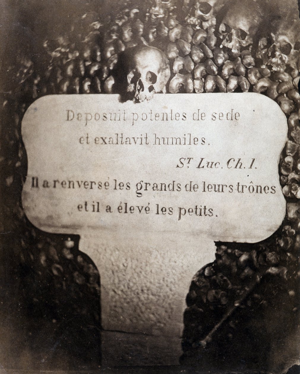 De beenderhuizen van de catacomben van Parijs. Peter met een citaat uit Hoofdstuk 1 van het Evangelie van Sint Lucas (Deposuit potentes de sede et exaltavit humiles. In het Frans: Hij wierp de groten omver en verhief de kleinen) door Nadar