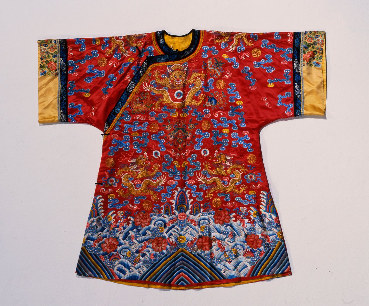 Een semi-formele mantel van rood satijn geborduurd met zijde en goud draad met draken te midden van scrollende wolken boven een turbulente zee golf rand door School Chinese