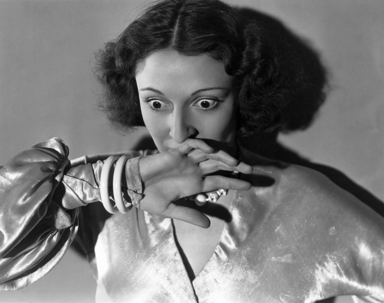 Hollywood, Californië: ca. 1932 Close-up van een Jonge Vrouw die haar Mond Bedekt uit Angst. (zw/w foto) door Unbekannt