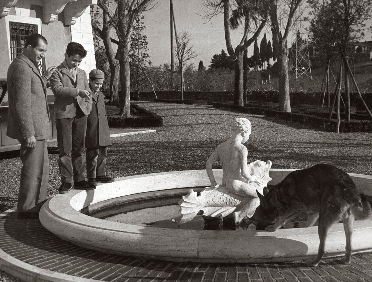 Gino Bartali met twee kinderen en een hond bij een fontein door Unknown photographer