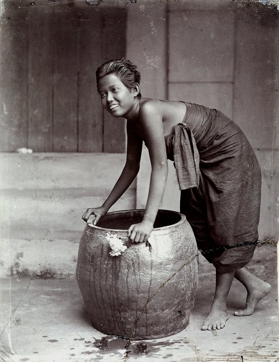 Jonge glimlachende Thaise vrouw, duwt een grote container door Unknown photographer