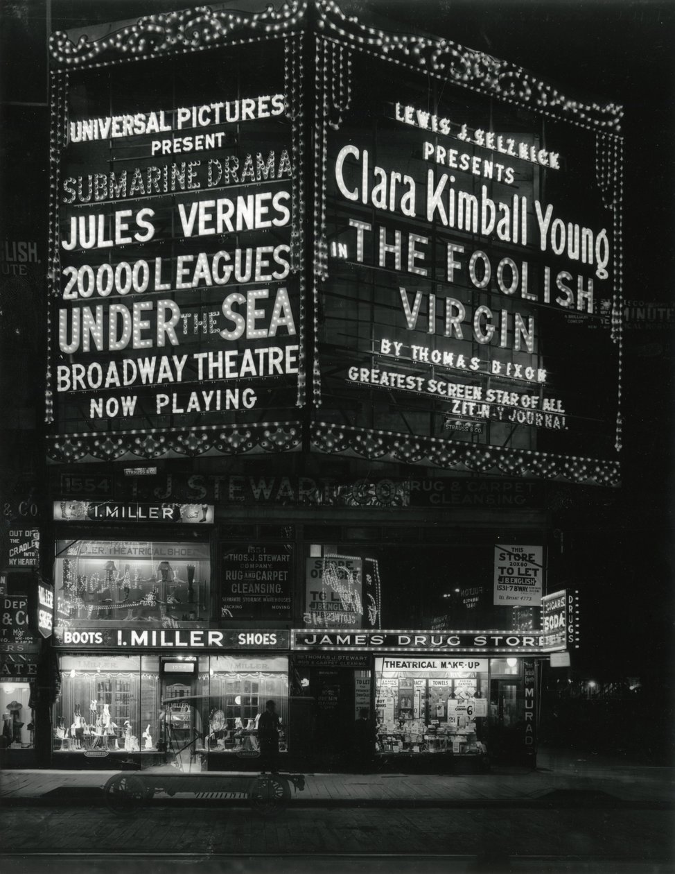 1554 Broadway op 46th Street, I. Miller Shoes; James Drug Store, en grote verlichte bioscoopmarquees erboven. door William Davis Hassler