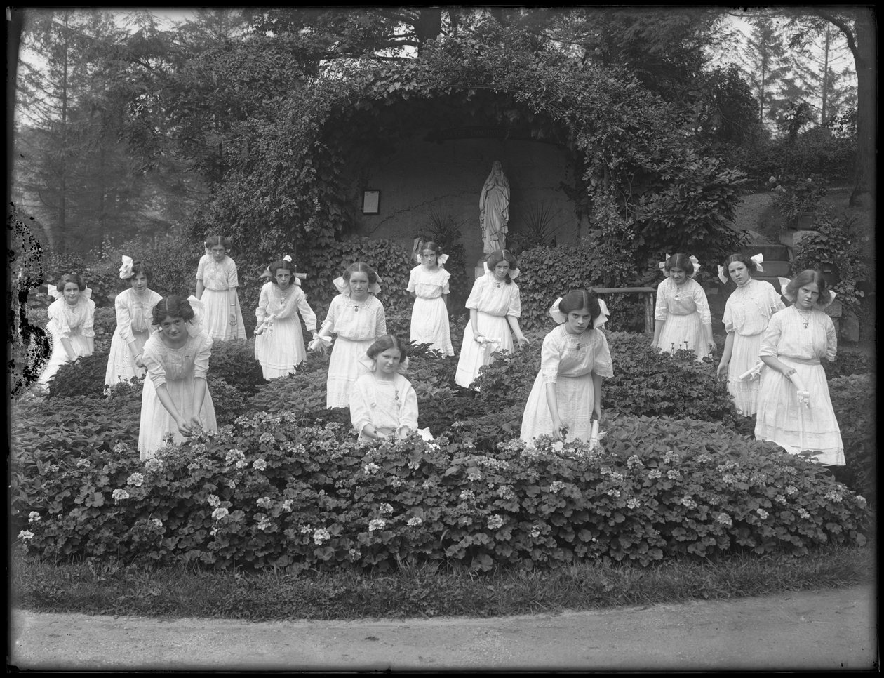 Afstudeerklas van meisjes van het Rooms-Katholieke Weeshuis in de bloementuin, voor de grot van de Maagd Maria, 1912 door William Davis Hassler