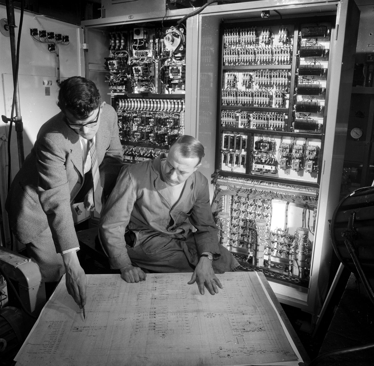 Ingenieurs bespreken plannen voor het elektronische bedieningspaneel dat ze hebben gebouwd door Frederick (attr. to) Barnard