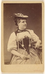 [Ongeïdentificeerde vrouw in klederdracht met hoed, zittend]. door A. Gabler