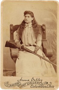 Annie Oakley: Hier zit de legendarische scherpschutter tamelijk bescheiden in een massieve Renaissance-stijl stoel, een geweer rustend op haar schoot. Haar delicate vrouwelijke trekken en vloeiende haar verbergen haar ruige buitenbeeld door American Photographer