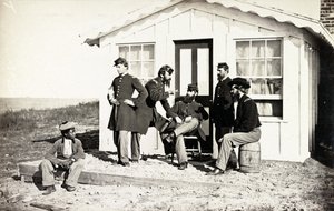 Vijf soldaten uit de Burgeroorlog verzameld op een veranda, Afro-Amerikaanse jongen zit bij hen, 1861-65