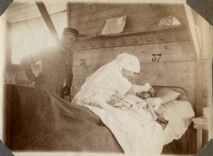 Eerste Wereldoorlog 1914-1918: verpleegster in een blouse scheert een soldaat (Franse oorlogswonden liggen in een bed), in Couville, Manche, Basse-Normandie, Frankrijk. Anonieme foto juli 1917. Privécollectie, Stella. door Anonymous Anonymous