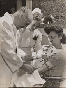 [Dokter en verpleegster steken een naald in de arm van een vrouw]. door Arnold Eagle