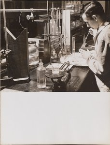 [Man in een lab gebruikt beide handen om een grote pipet in een bekerglas te plaatsen]. door Arnold Eagle