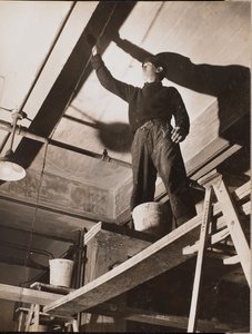 [Een man op een houten steiger schildert een plafond].