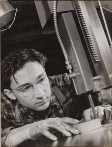 [Man met bril werkt geconcentreerd met een industriële vijl]. door Arnold Eagle