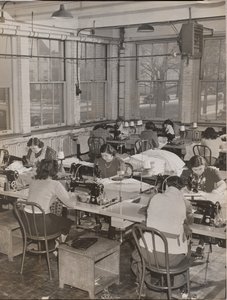 [Vrouwen aan bureaus werken aan naaimachines]. door Arnold Eagle
