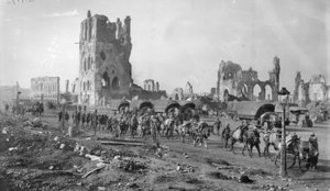 Een niet-geïdentificeerde Australische machinegeweersectie met bepakte paarden die de ruïnes van de Lakenhal passeren. Let op de geparkeerde motorvrachtwagens op de achtergrond, 19 oktober 1917