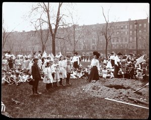 Volwassenen en kinderen met vlaggen staan rond een nieuw gegraven gat voor een boomplanting op Arbor Day in Tompkins Square Park, New York