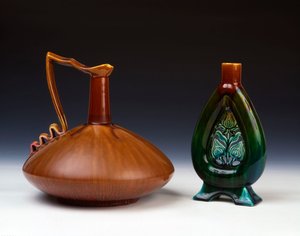 Een Linthorpe aardewerken kan van samengedrukte bolvorm met streperige karamel, groene en karmozijnrode glazuur en een Linthorpe aardewerken vaas met doorboorde bloemknopdecoratie en gevlekte groene, blauwe en bruine glazuren door Christopher Dresser
