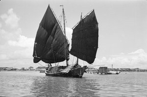 Een belstam havenjunkschip onder zeil in Singapore