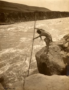 Tlakluit Indiaan, staand op rots, vist met schepnet, ca. 1910 (z/w foto) door Edward Sheriff Curtis