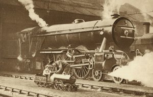 Jongen rijdt op een speelgoedstoomlocomotief voor de echte (z/w foto) door English Photographer