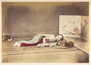 Japanse vrouw die slaapt, Studioportret van een jonge Japanse vrouw die slaapt, met een ontbloot borst en haar hoofd rustend op een houten kussen