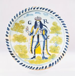 Een Bristol Delft polychroom koninklijk portret bord beschilderd met een volledige lengte portret van George I in formele gewaden, ca. 1720