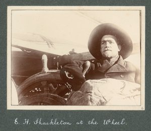 E H Shackleton staand bij het stuur van de 