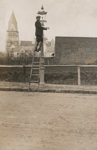 Man op een ladder die een straatlantaarn repareert