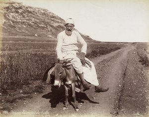 Portret van een boer uit de omgeving van Haifa. De man rijdt op een ezel