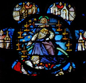 Het westelijke roosvenster met een scène uit het Boek Openbaring: Christus op een regenboog omgeven door zeven gouden kandelaren en de zeven kerken van Azië. In zijn mond is het scherpe tweesnijdende zwaard door French School