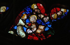 Het westelijke roosvenster met een scène uit het Boek Openbaring: hoofden van de zeven donderslagen (in een blauwe wolk) en St. Johannes die verboden wordt te schrijven (10:3-5)